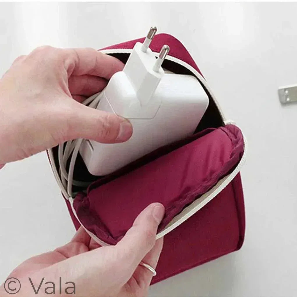 Person inserting a white power adapter into a red travel adapter case.